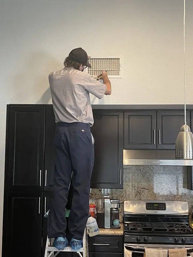 Technician inspecting an air vent during HVAC service in Findlay